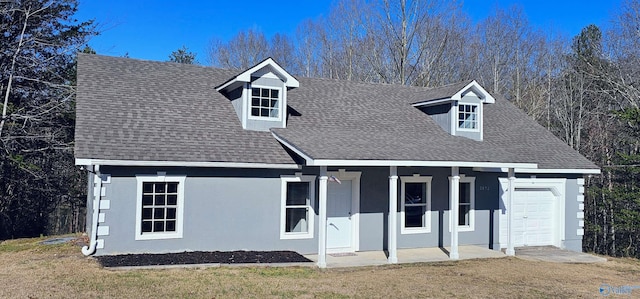 cape cod-style house with stucco siding, a shingled roof, covered porch, an attached garage, and a front lawn