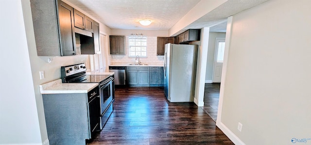 kitchen featuring decorative backsplash, appliances with stainless steel finishes, dark wood-style flooring, light countertops, and a sink