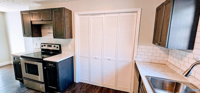 kitchen with light countertops, backsplash, electric range, dark wood-type flooring, and a sink