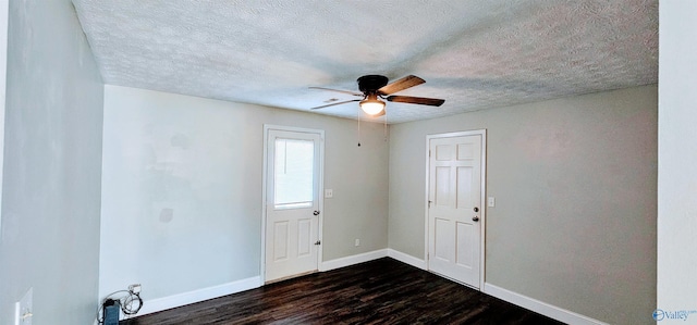 spare room with ceiling fan, a textured ceiling, baseboards, and dark wood-type flooring