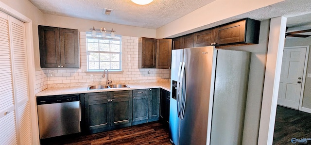 kitchen featuring appliances with stainless steel finishes, dark wood-type flooring, a sink, and light countertops