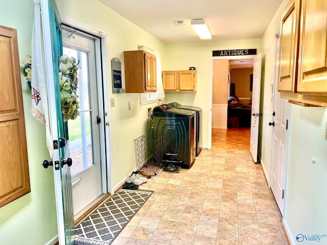 clothes washing area with cabinets, independent washer and dryer, and a textured ceiling