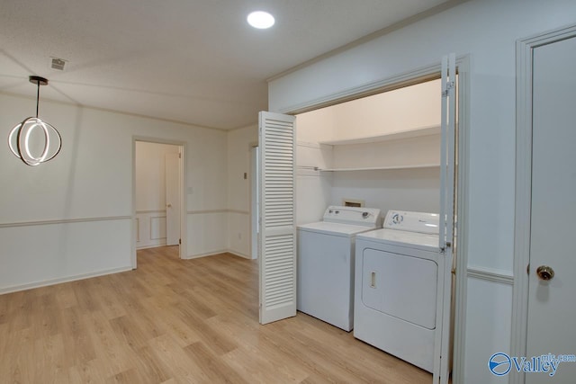 washroom with visible vents, independent washer and dryer, light wood-style floors, baseboards, and laundry area