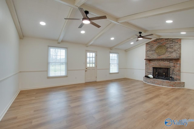 unfurnished living room with light wood-type flooring, a ceiling fan, lofted ceiling with beams, baseboards, and a brick fireplace