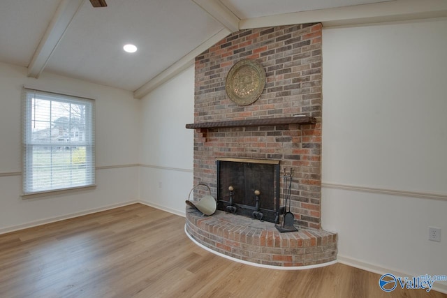 unfurnished living room with lofted ceiling with beams, a brick fireplace, wood finished floors, and baseboards