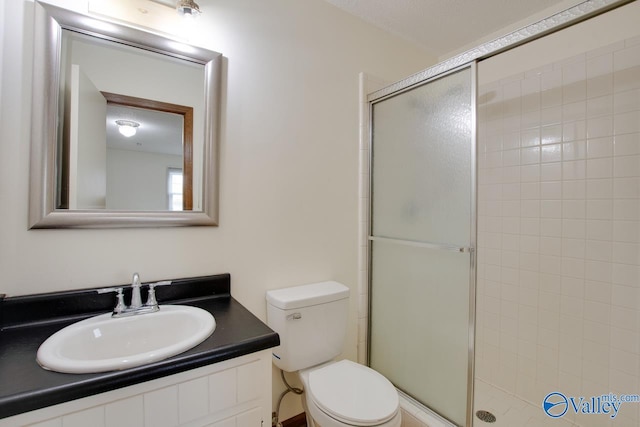 bathroom with a stall shower, toilet, and vanity