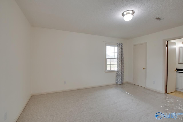 unfurnished bedroom with light carpet, visible vents, baseboards, and a textured ceiling