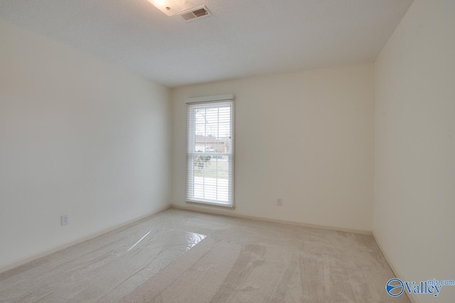 unfurnished room with light carpet, visible vents, and baseboards