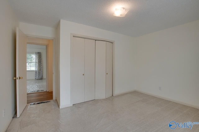 unfurnished bedroom with baseboards, carpet, a closet, and a textured ceiling