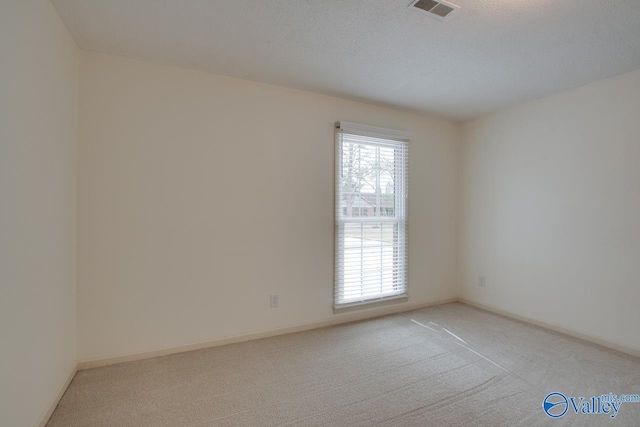 spare room with baseboards, visible vents, and light carpet