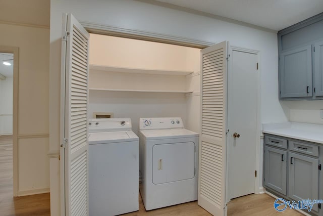 laundry area with laundry area, light wood-style flooring, ornamental molding, and washer and clothes dryer