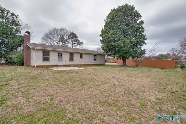 rear view of house with a yard, a chimney, and a patio