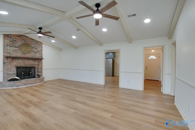 unfurnished living room featuring light wood finished floors, visible vents, a brick fireplace, lofted ceiling with beams, and a ceiling fan