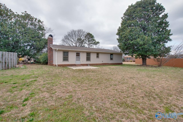 back of property with a patio, fence, a lawn, and a chimney