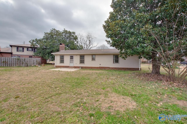 back of property with a patio area, a lawn, a chimney, and fence