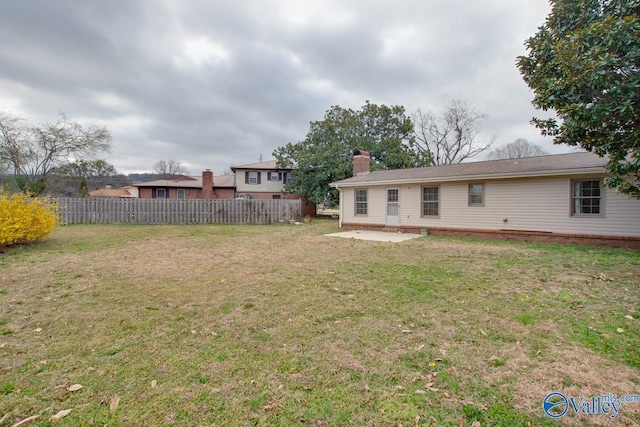 back of house featuring a patio area, fence, a lawn, and a chimney