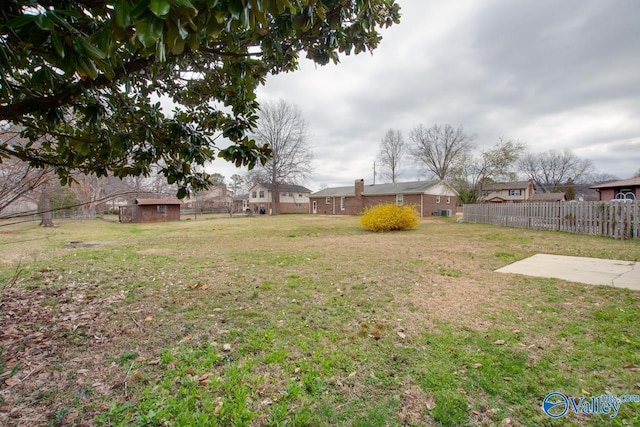 view of yard with an outbuilding, fence, and a shed