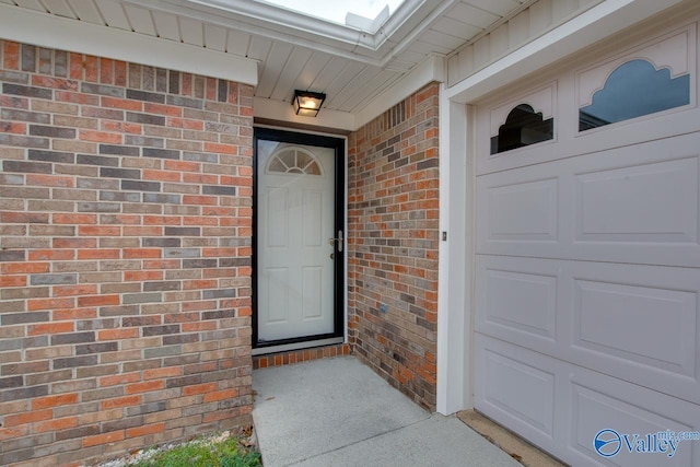 doorway to property with brick siding and a garage