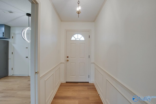 entryway featuring visible vents, light wood-style floors, and crown molding