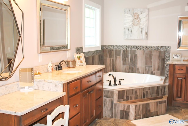 bathroom with tiled tub and vanity