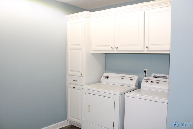 clothes washing area featuring washer and clothes dryer and cabinets