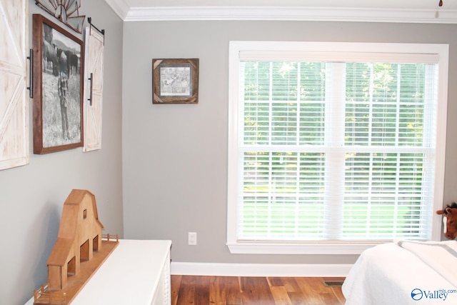 bedroom with multiple windows, crown molding, and hardwood / wood-style flooring