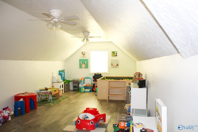 rec room with a textured ceiling, lofted ceiling, ceiling fan, and hardwood / wood-style flooring