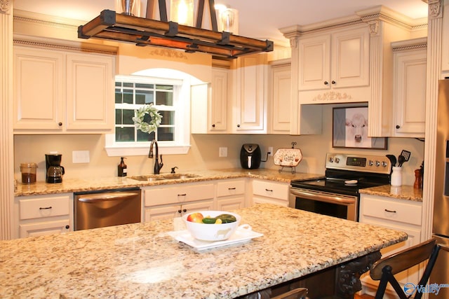 kitchen featuring light stone counters, a breakfast bar area, sink, appliances with stainless steel finishes, and decorative light fixtures