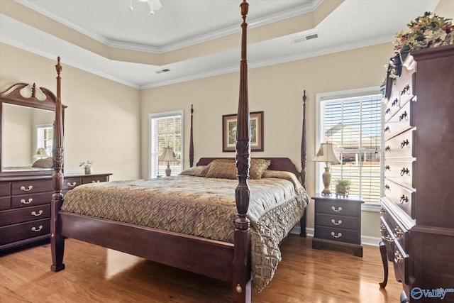 bedroom with a raised ceiling, ornamental molding, and multiple windows