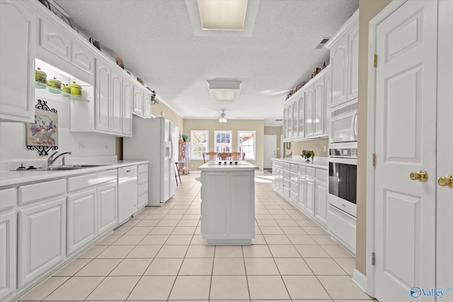 kitchen with white appliances, light tile patterned floors, and white cabinets