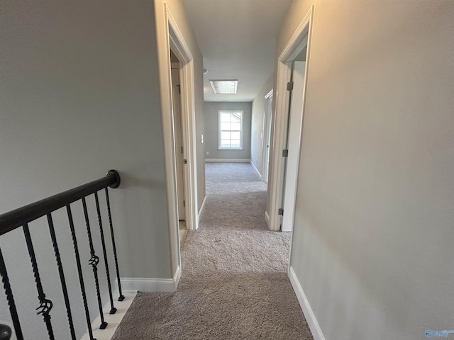 hallway with light carpet and a skylight