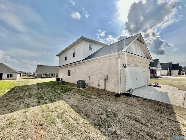 view of side of property featuring cooling unit, a garage, and a yard