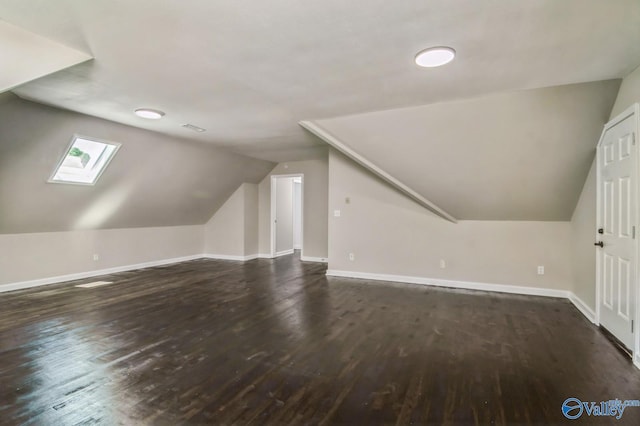 additional living space featuring dark hardwood / wood-style flooring and vaulted ceiling with skylight