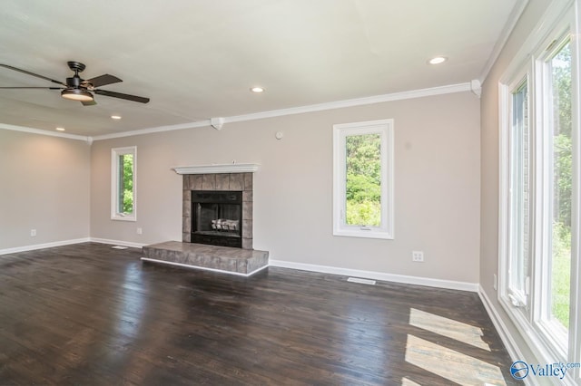 unfurnished living room with a tiled fireplace, crown molding, dark hardwood / wood-style flooring, and ceiling fan