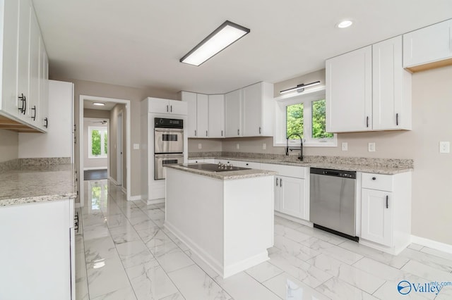 kitchen featuring stainless steel appliances, sink, white cabinetry, a kitchen island, and a healthy amount of sunlight