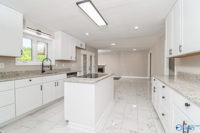 kitchen with a kitchen island, white cabinetry, sink, light stone counters, and black electric cooktop