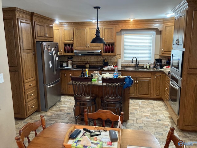 kitchen with sink, tasteful backsplash, decorative light fixtures, a kitchen bar, and appliances with stainless steel finishes