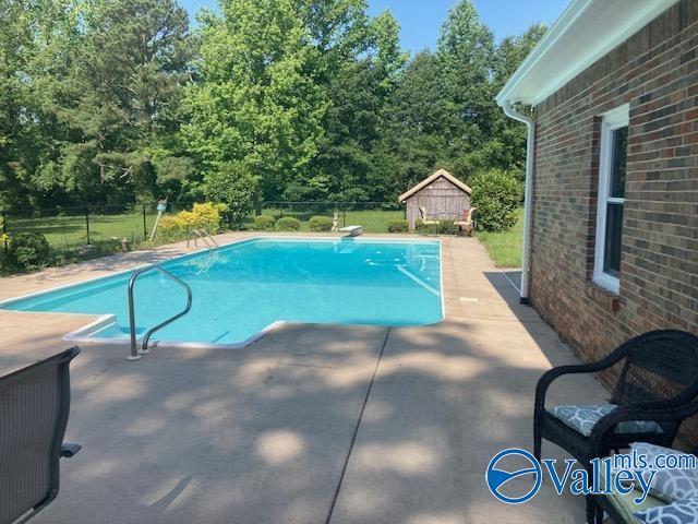 809 Kyle Rd NE, Hartselle, AL 35640 - outdoor pool with a patio, an outbuilding, view of scattered trees, and a diving board
