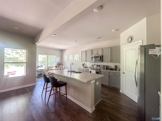 117 Edensmith Dr, New Market, AL 35761 - kitchen featuring stainless steel appliances, a sink, gray cabinets, dark wood-style floors, and a center island with sink
