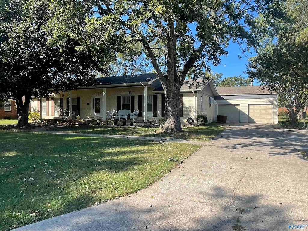 view of front of property featuring covered porch, a front yard, and a garage