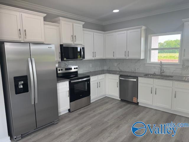 17194 Red Hill Rd, Athens, AL 35611 - kitchen featuring stainless steel appliances, white cabinetry, light wood-style flooring, recessed lighting, and crown molding