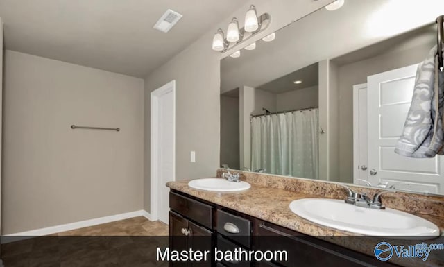 bathroom with double vanity, baseboards, visible vents, and a sink