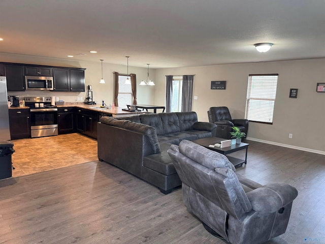 living room with light wood finished floors, recessed lighting, and baseboards