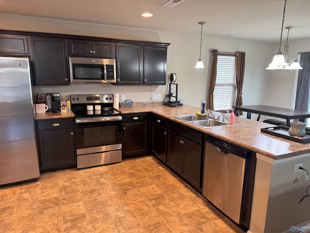 kitchen with pendant lighting, a sink, recessed lighting, appliances with stainless steel finishes, and a peninsula