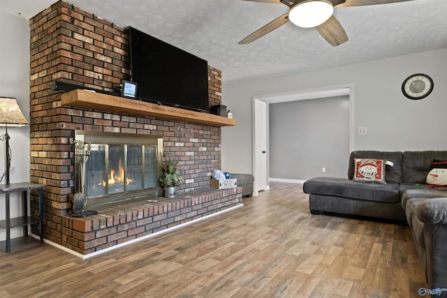 living room with a fireplace, wood-type flooring, a textured ceiling, and ceiling fan