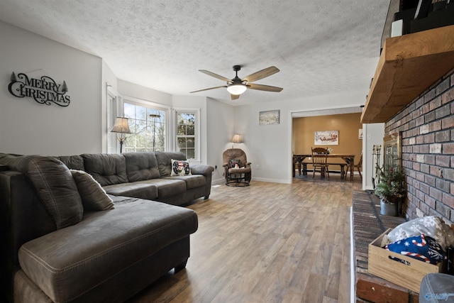 living room with a fireplace, wood-type flooring, a textured ceiling, and ceiling fan