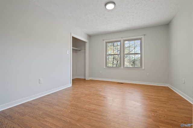 unfurnished bedroom featuring a textured ceiling, light hardwood / wood-style floors, and a closet