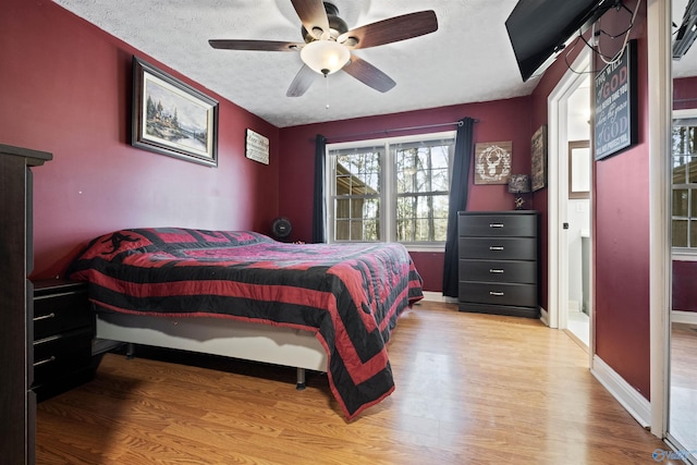 bedroom with ceiling fan, light hardwood / wood-style floors, and a textured ceiling