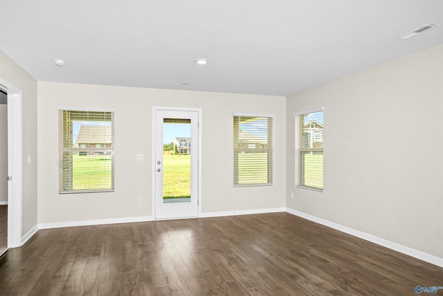 unfurnished room with dark hardwood / wood-style flooring and a healthy amount of sunlight