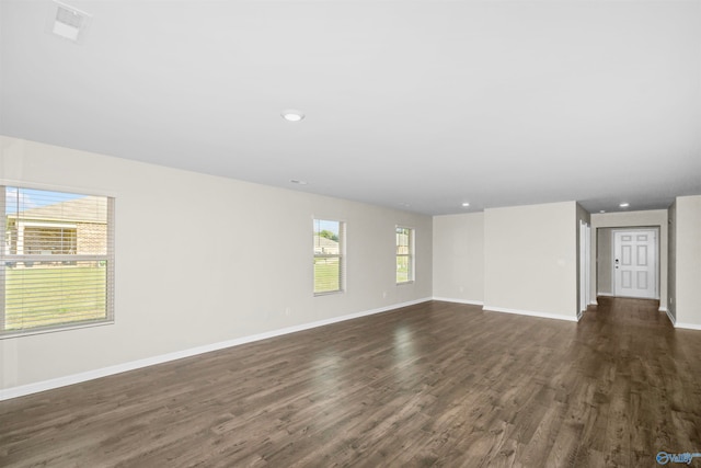 empty room with dark hardwood / wood-style floors and a healthy amount of sunlight